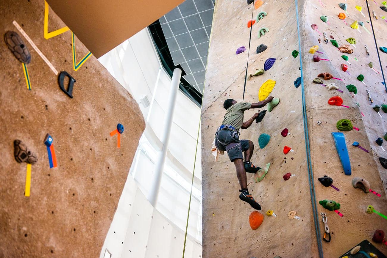 Student climbing rock wall.